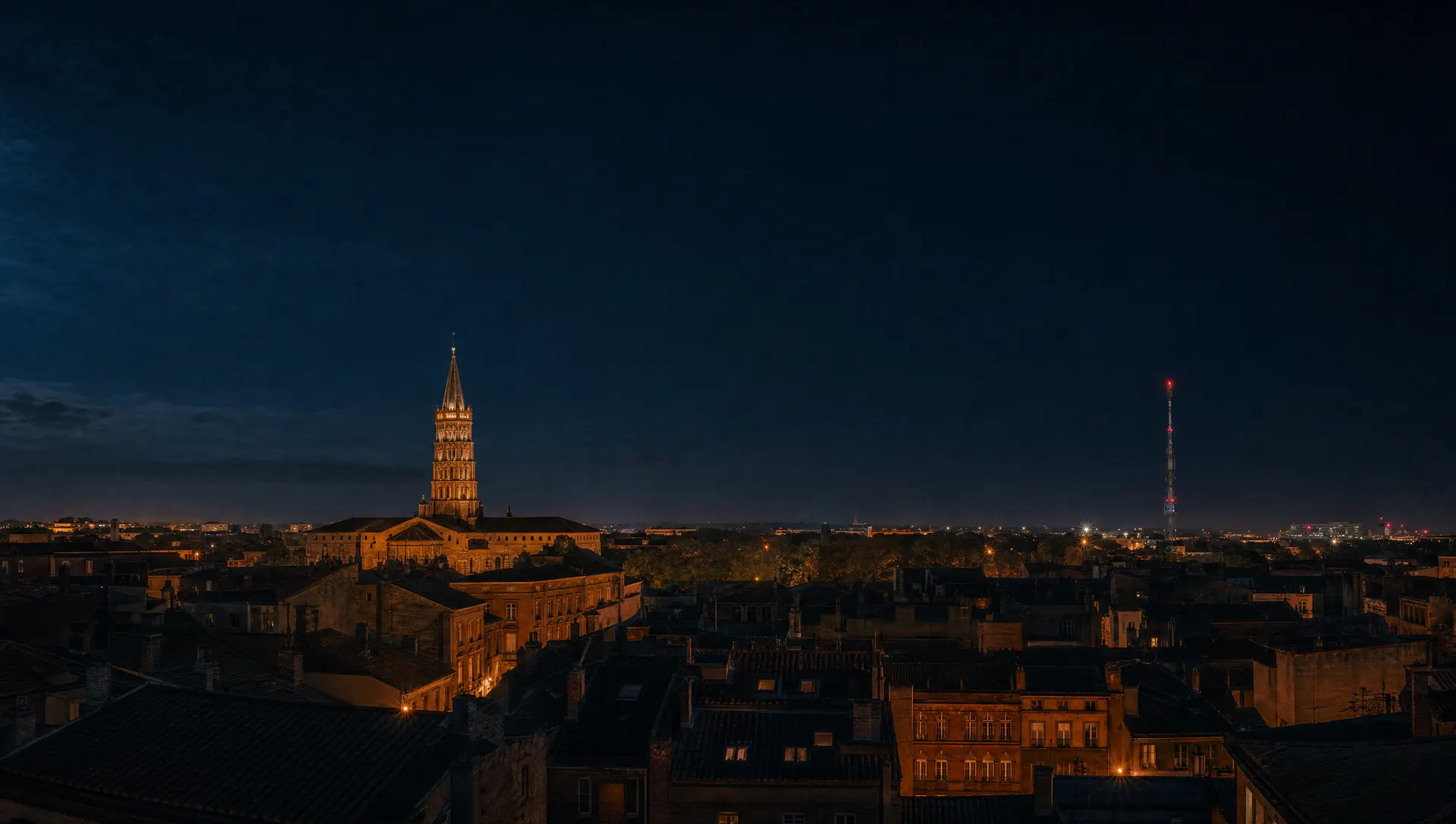 Toulouse de nuit, la basilique Saint-Sernin illuminée et, au loin, l'émetteur radio